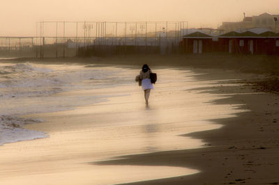 Full length of man walking on beach against sky