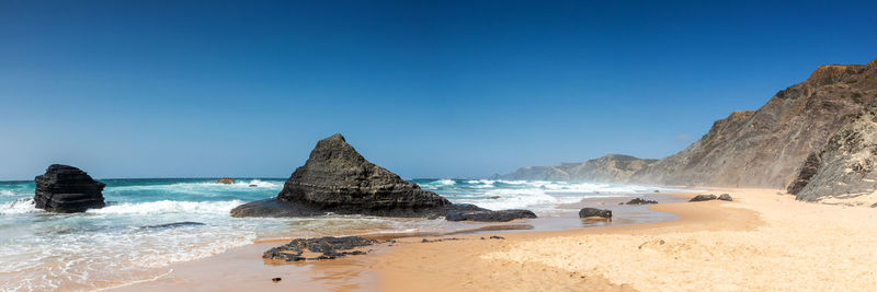 Panoramic view of beach against clear blue sky