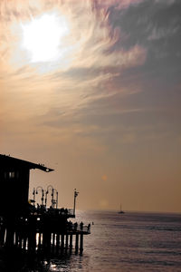 Silhouette built structure by sea against sky during sunset