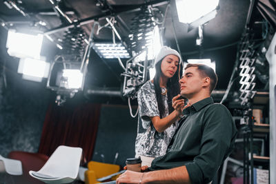 Young man is preparing for tv online broadcast. woman helps with make up.