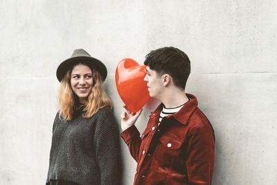 Young man and woman standing against wall