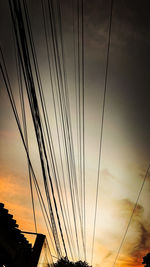 Low angle view of silhouette cables against sky at sunset