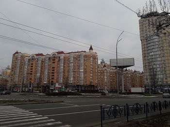 Road by buildings against sky in city