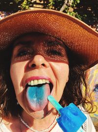 Close-up portrait of smiling woman sticking out tongue while holding popsicle