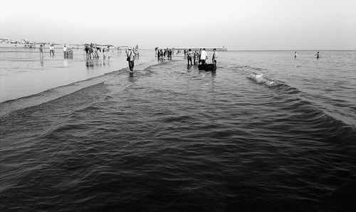 People on beach against clear sky