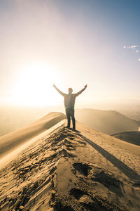 Full length of man standing on street against sky during sunset