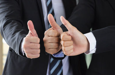 Cropped hands of businesspeople gesturing thumbs up
