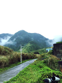 Road leading towards mountains against clear sky