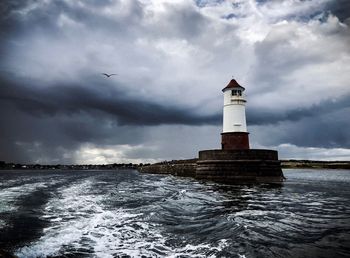 Lighthouse by sea against sky