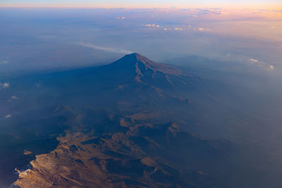 Aerial view of snowcapped mountains against sky at sunset