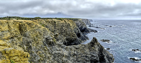 Rock formations by sea against sky