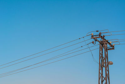 Low angle view of electricity pylon against blue sky