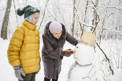 Boy making snowman with grandmother in park