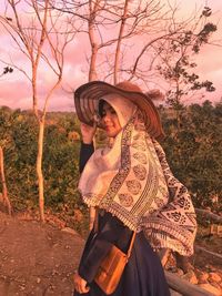 Woman standing on field against trees