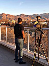 Rear view of man photographing against sky