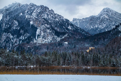 Scenic view of lake by mountains against sky during winter