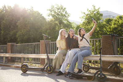 Young female friends spending time together outdoors and taking selfie