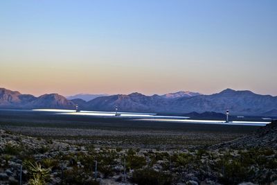Scenic view of sea and mountains against clear sky