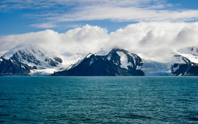 Scenic view of sea and snowcapped mountains against sky