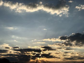 Low angle view of sunlight streaming through clouds