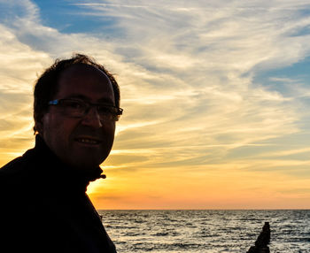 Portrait of man wearing eyeglasses against cloudy sky during sunset