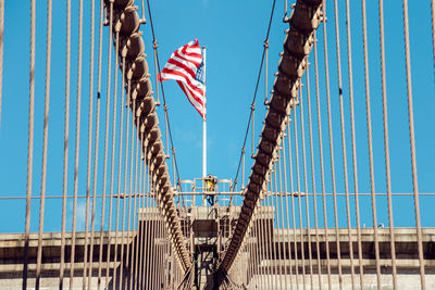 Low angle view of suspension bridge against blue sky with american flag