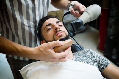 Midsection of barber combing man beard