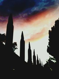 Low angle view of silhouette trees against cloudy sky