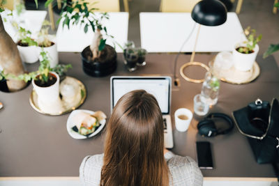 High angle view of businesswoman using laptop while sitting at desk in office cafe