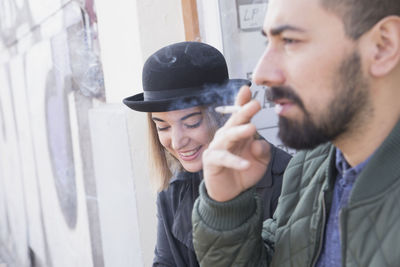 Young man smoking beside his smiling girlfriend