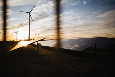 Scenic view of wind turbines on land against sky during sunset