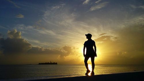 Silhouette of people standing on beach at sunset