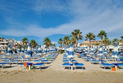 Panoramic view of chairs on beach against blue sky