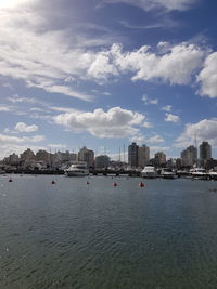 Cityscape by river against sky