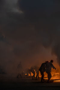 Silhouette people on land against sky during sunset