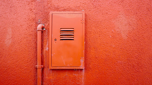 Metal pipe and electric box on orange color wall in burano, venice, italy