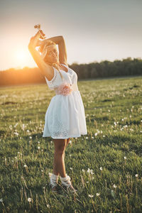 Woman standing on field against sky during sunset