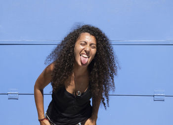 Portrait of smiling arabic young woman against blue wall