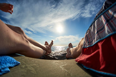 People relaxing on beach against sky