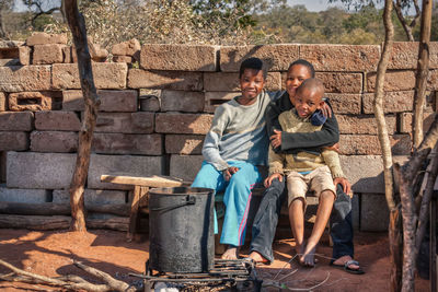 Portrait of siblings sitting against wall