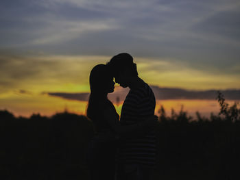 Silhouette woman standing against orange sky