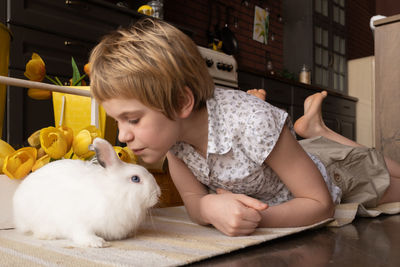 Girl kissing rabbit at home