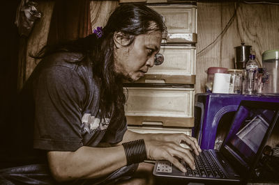 Side view of man working on laptop at home