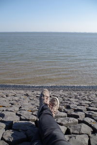 Low section of person on beach against sky