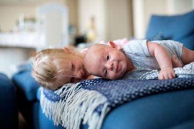 Sister with baby boy relaxing on bed at home