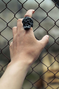 Midsection of person holding chainlink fence