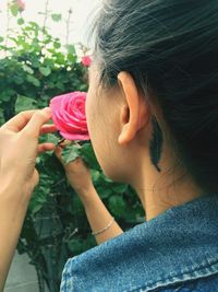 Rear view of female smelling rose