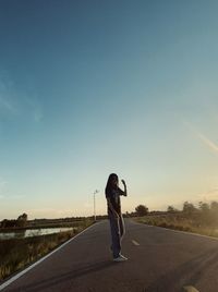 Rear view of man walking on road against clear sky