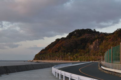 Empty road by sea against sky