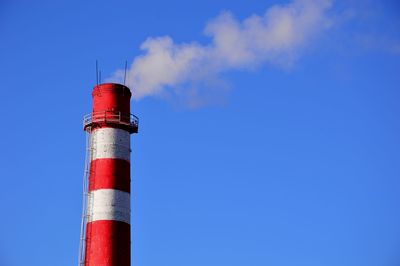 Low angle view of smoke stacks against blue sky